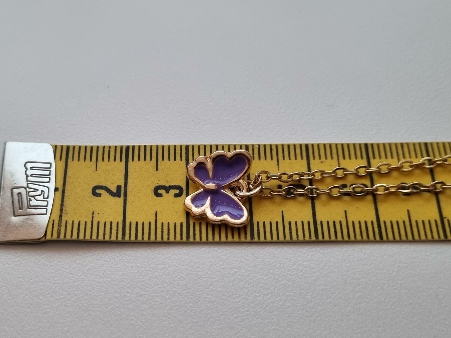 Guldfärgat halsband med en lila fjäril / fjärilsberlock