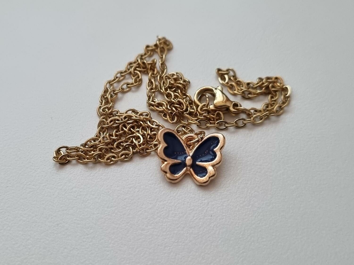 Guldfärgat halsband med en svart fjäril / fjärilsberlock
