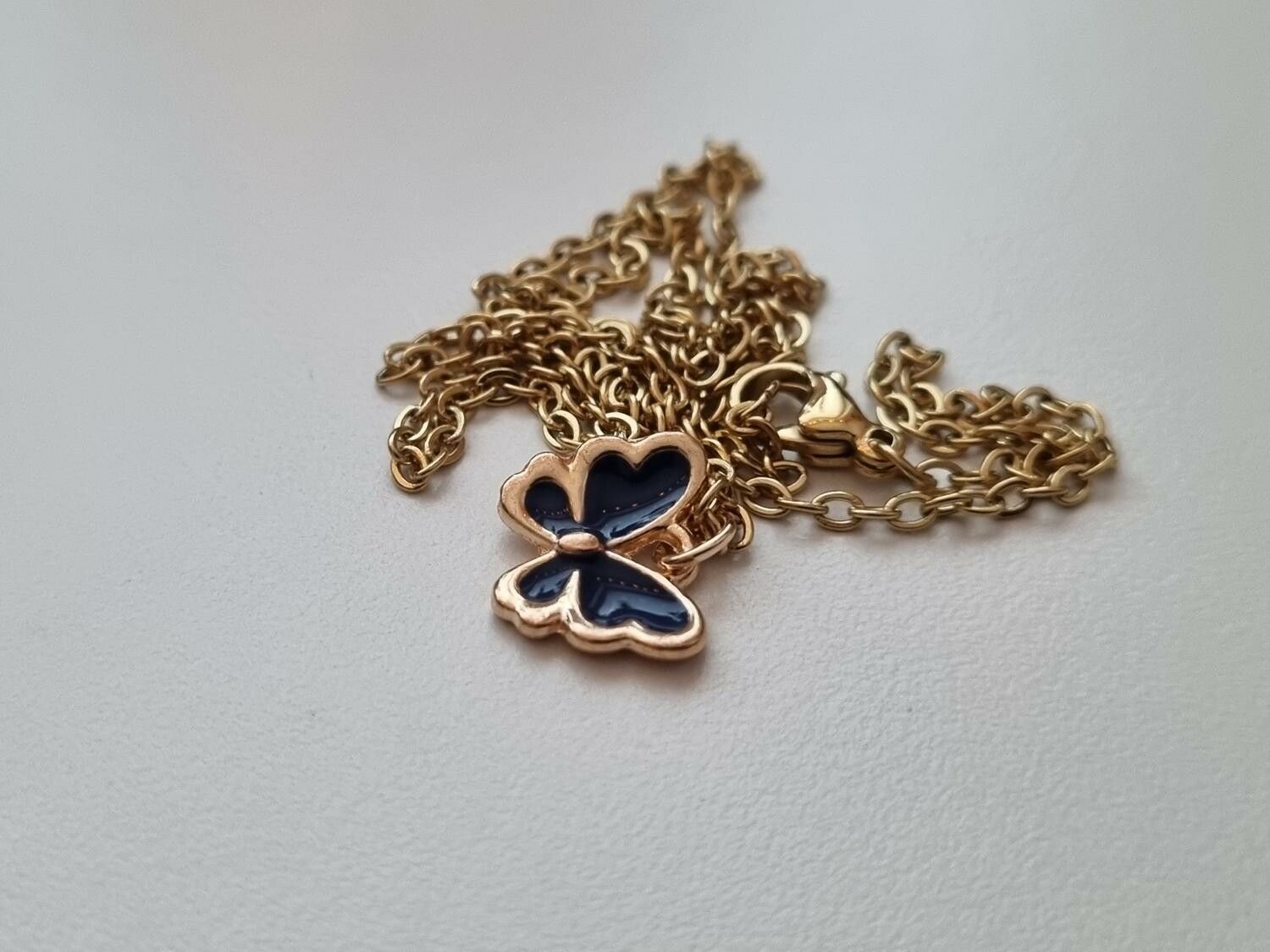 Guldfärgat halsband med en svart fjäril / fjärilsberlock