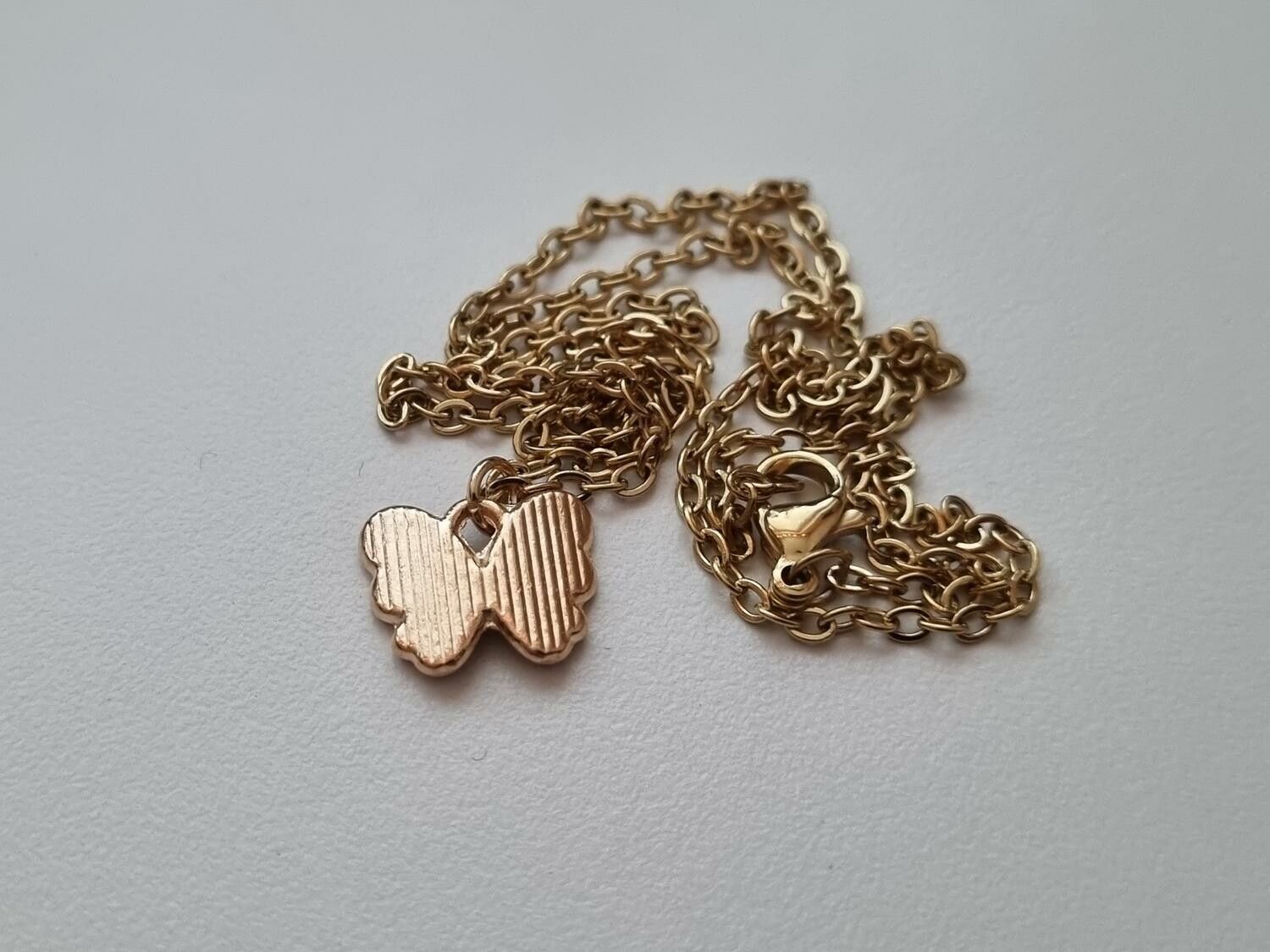 Guldfärgat halsband med en svart fjäril / fjärilsberlock