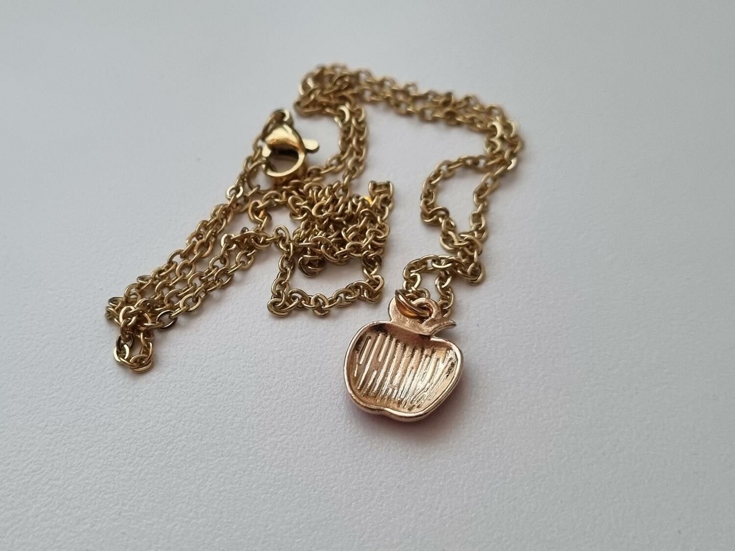Guldfärgat halsband med ett äpple / äppleberlock