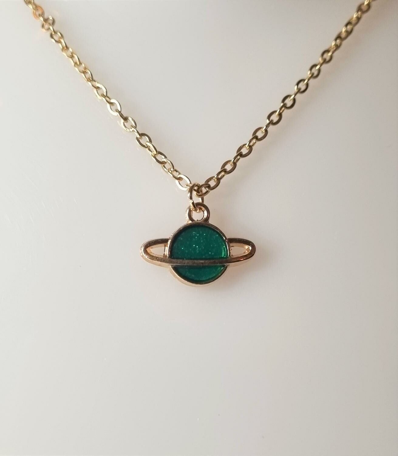 Guldfärgat halsband med en grön planet, berlock / charm