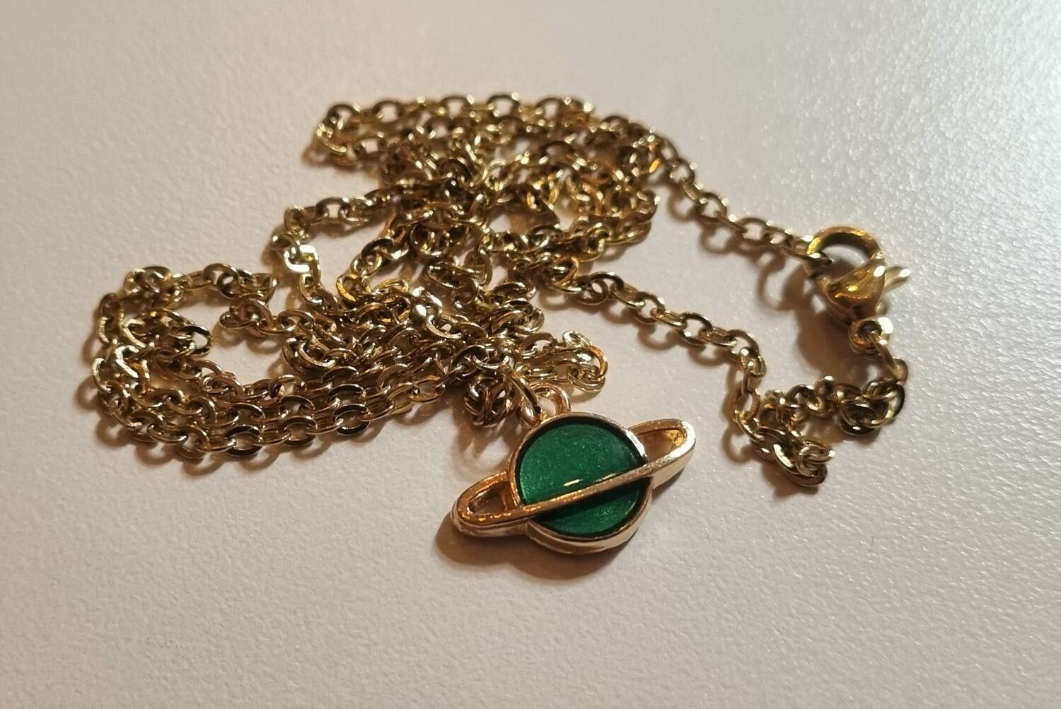 Guldfärgat halsband med en grön planet, berlock / charm