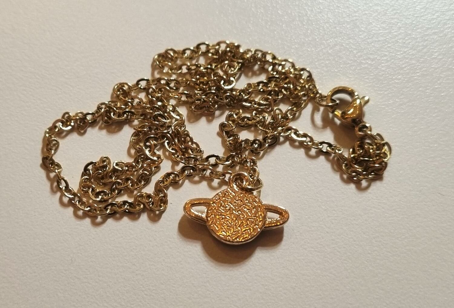 Guldfärgat halsband med en grön planet, berlock / charm