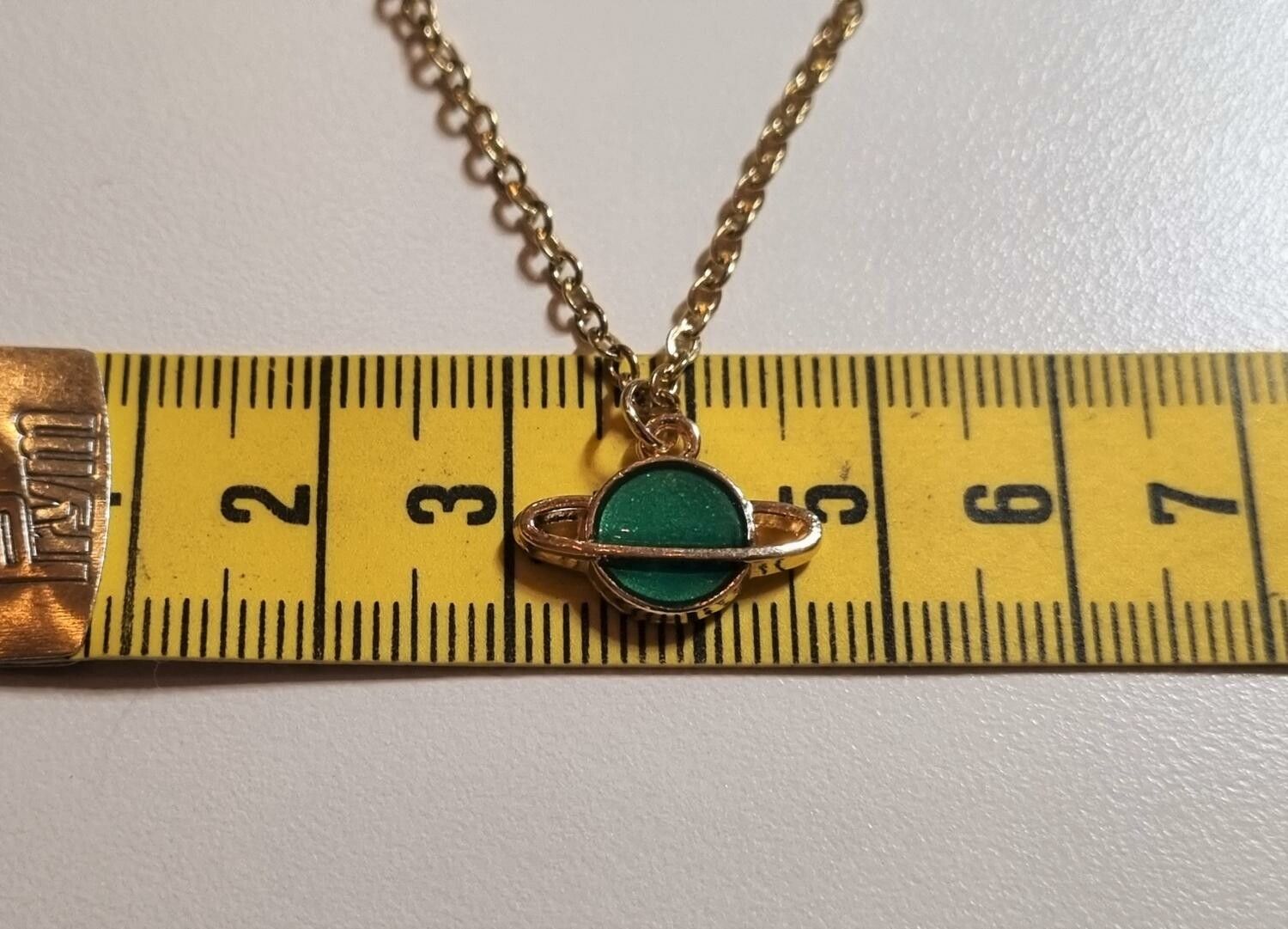 Guldfärgat halsband med en grön planet, berlock / charm