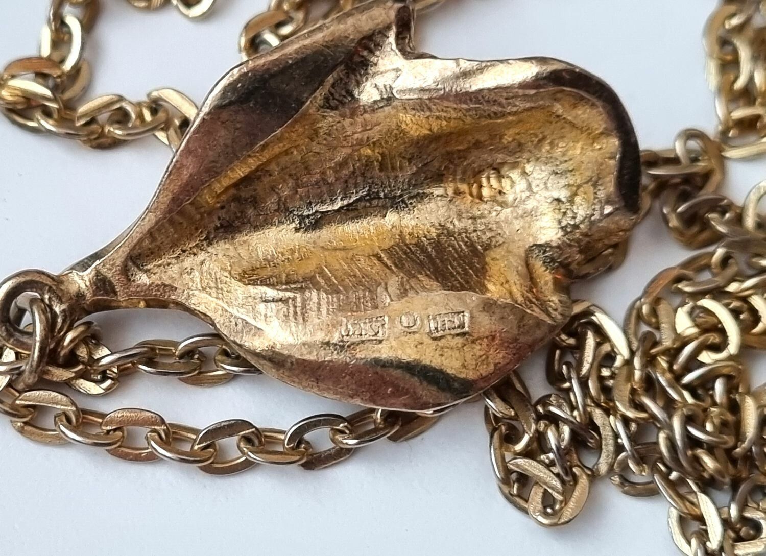 Guldfärgat halsband med ros. Svårtydda stämplar