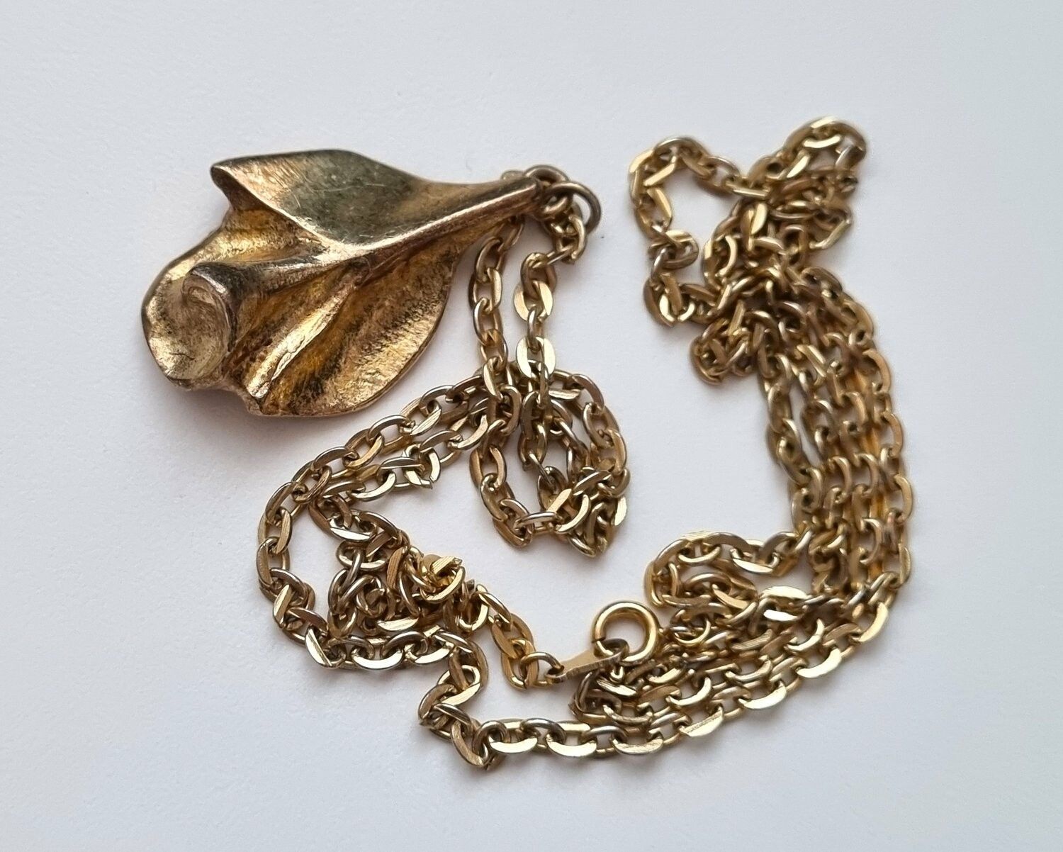 Guldfärgat halsband med ros. Svårtydda stämplar