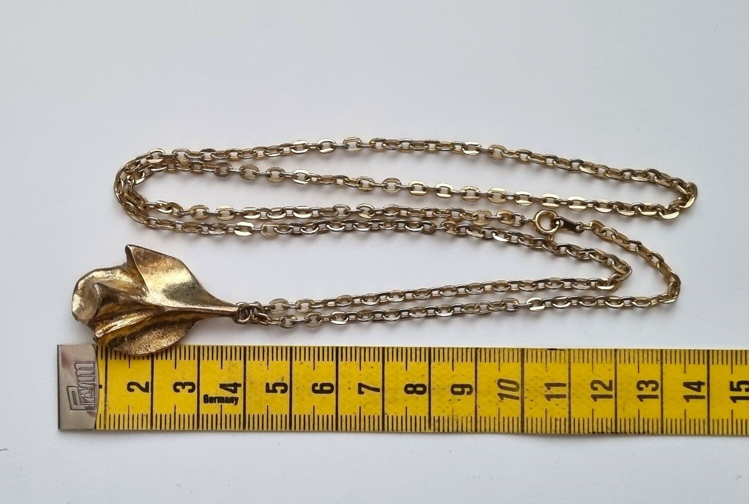 Guldfärgat halsband med ros. Svårtydda stämplar
