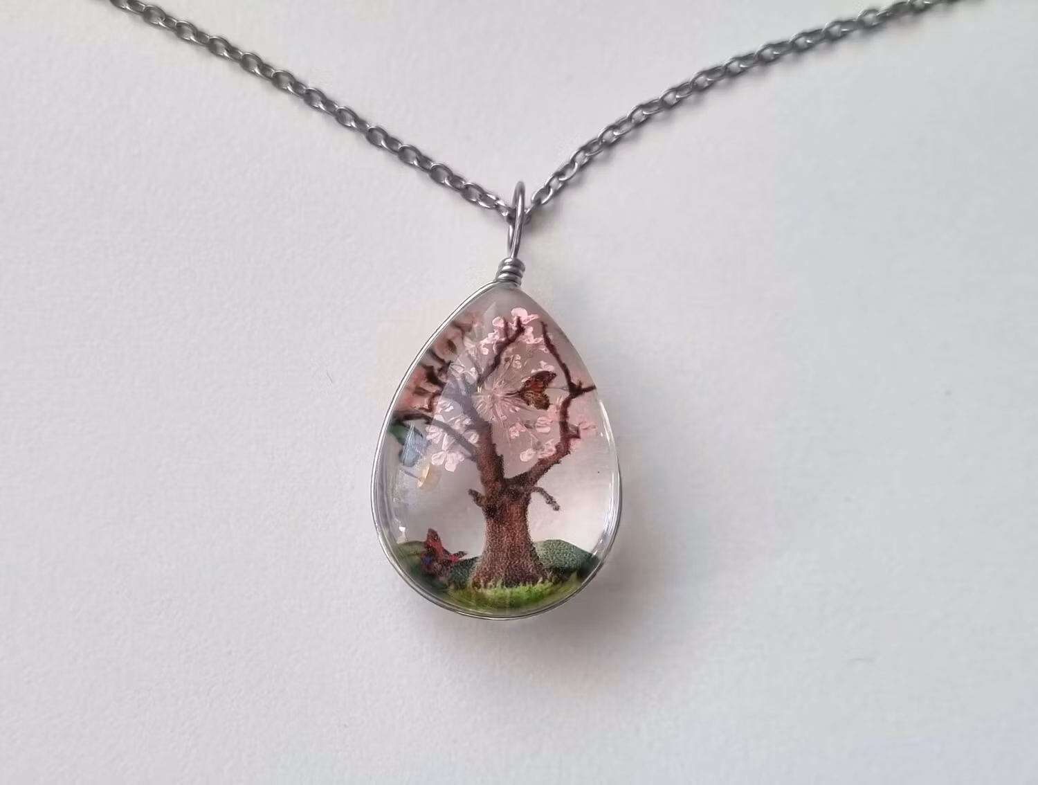 Halsband oval glasberlock motiv av träd och fjärilar, ljusrosa