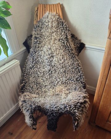 Fårskinn med kort grå/brun päls och mörkbruna kanter.