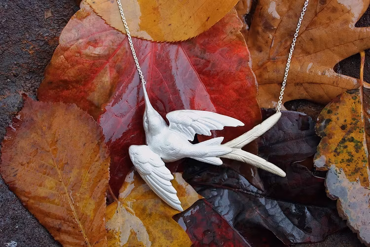 Fluttering Swallow Halsband från Lotta Jewellery är gjort i 925 sterling silver med dekorationer i 14 k guld. Genom att låta vita safirer utgöra ögonen på svalan har vi gett den vackra fågeln lite ext