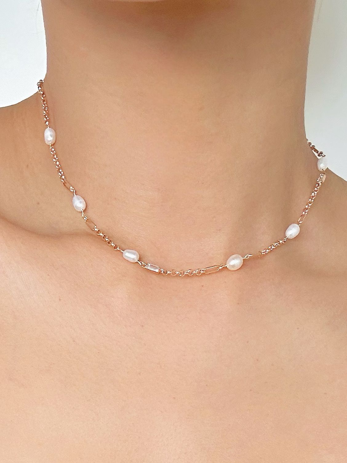 Tunt guldfärgat halsband med ovala vita pärlor