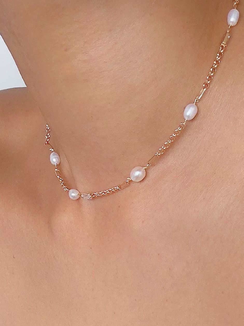 Tunt guldfärgat halsband med ovala vita pärlor