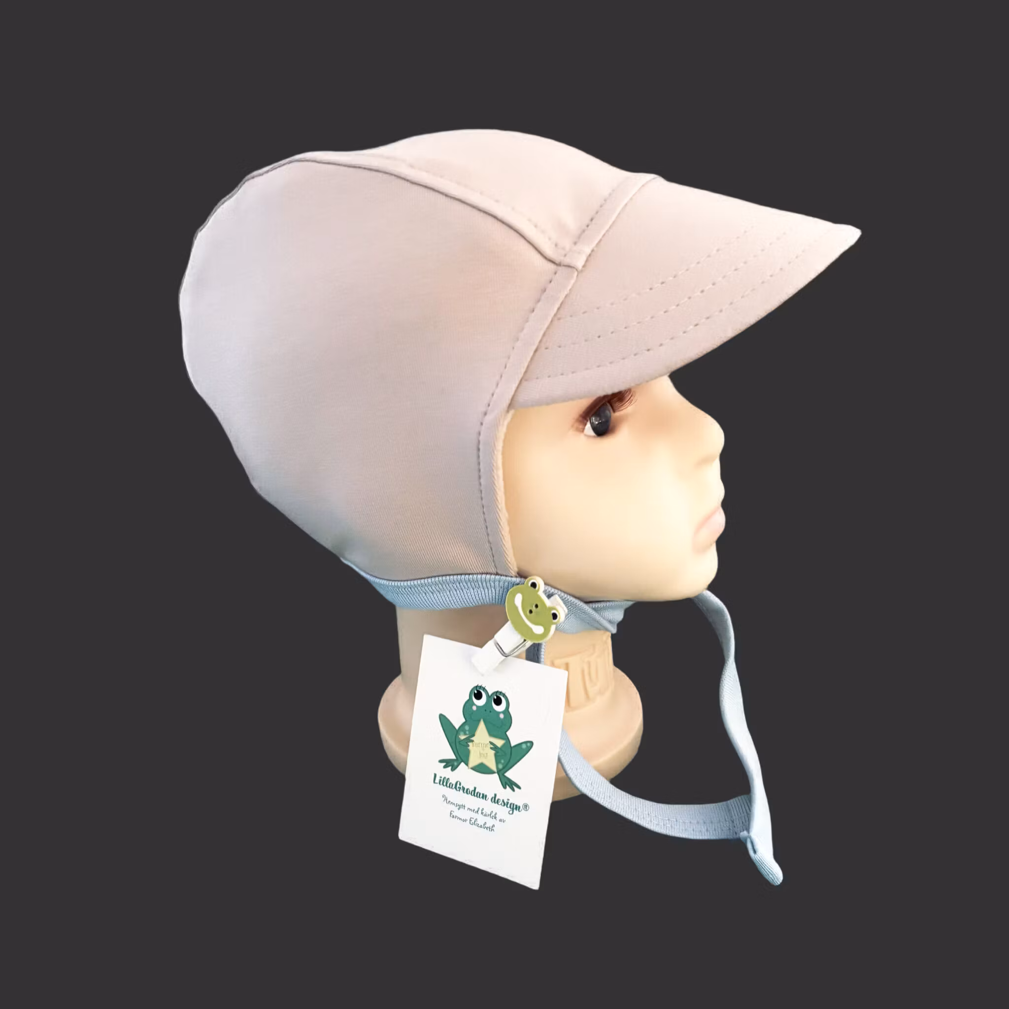 Hjälmmössa i tyg Sand, knytband i ljusblått