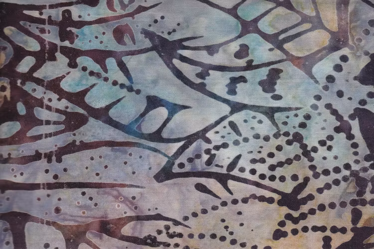 Blekt flerfärgad botten med mörka stilistiska bladmotiv. Balibatik