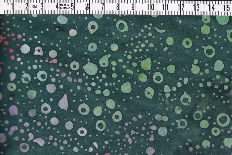 Mörkgrönmelerat med prickar och ringar i flera färger.