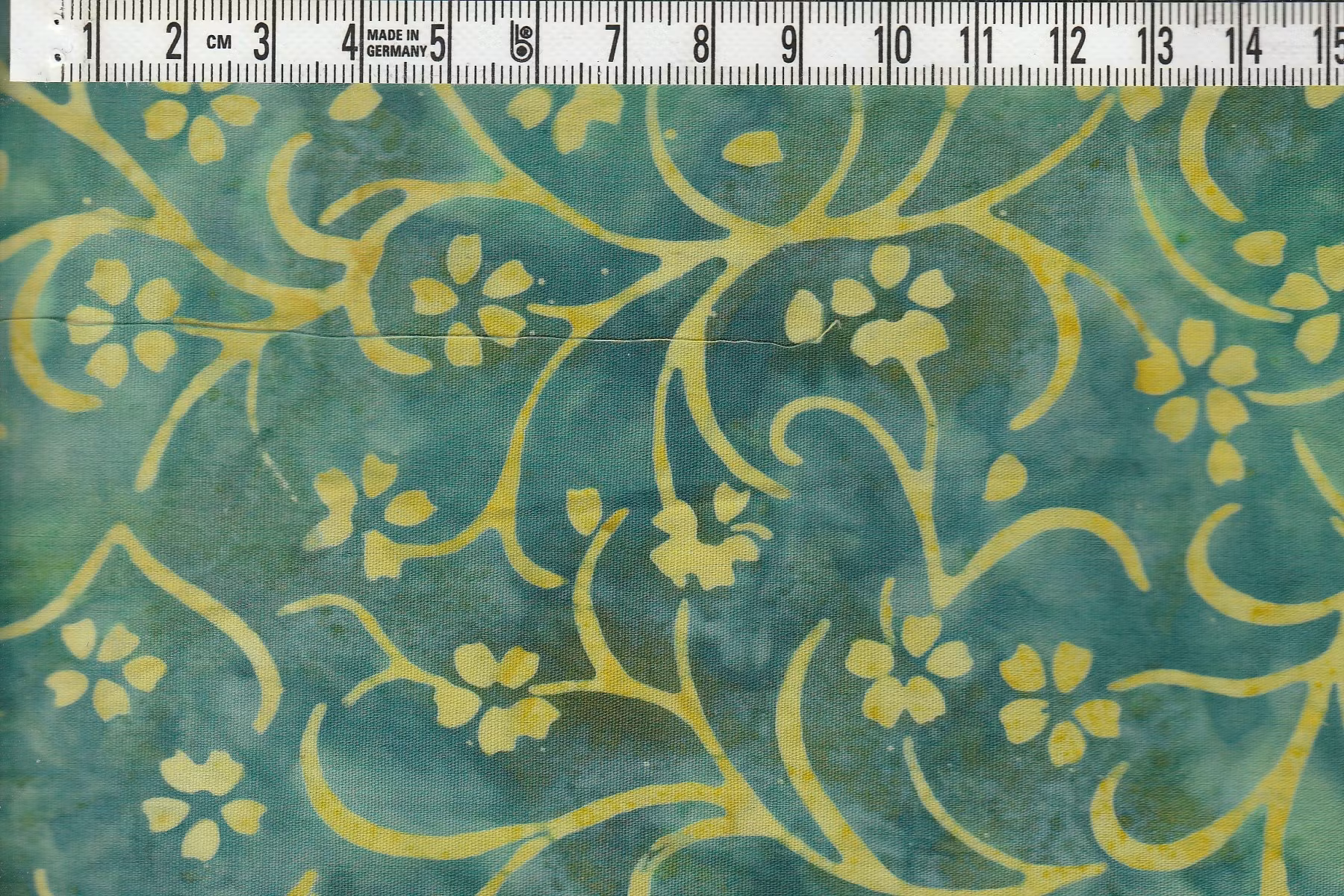 Snirkliga blommor i gult på grönmelerat. Balibatik