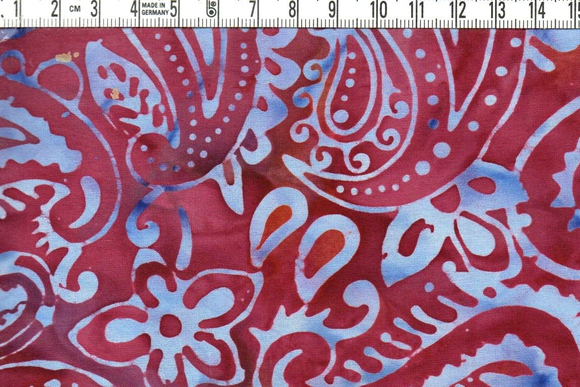 Stora paisley i blått på karminröd. Bomullsbatik bredd 110 cm