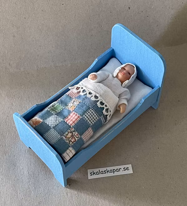 Liten blå säng med lapptäcke