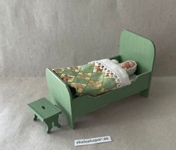 Liten grön säng med lapptäcke