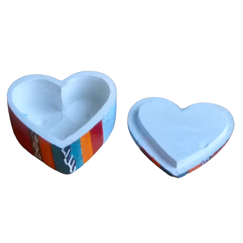 Hjärtformad nipperask i täljsten. 5x5cm. Locket är avtagen och ligger bredvid, men insidan uppe. Dekorerad med målat och inristat mönster. Insidan ofärgad. Fair Trade Kenya.