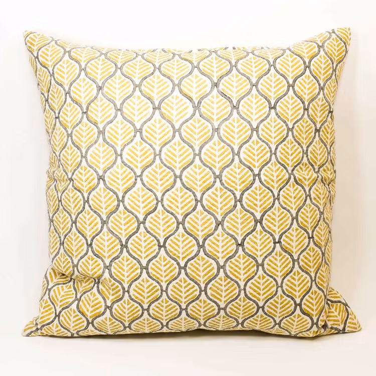 Kudde helmönstrad med gult och grått på vit botten.