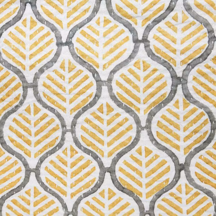 Kudde helmönstrad med gult och grått på vit botten. Närbild.