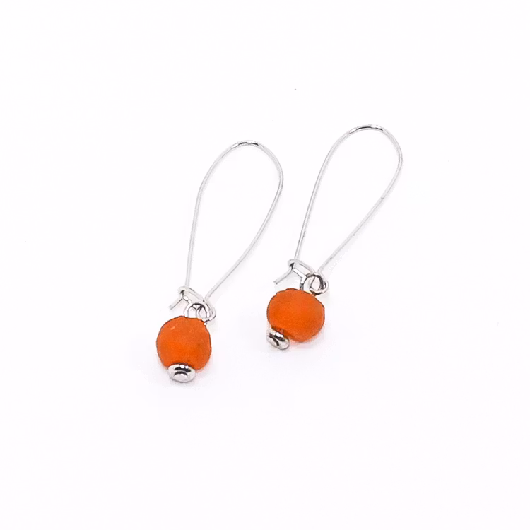 Ett par örhängen med var sin orange pärla av återvunnet glas.