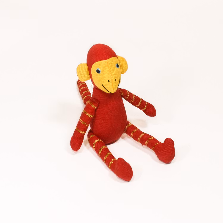 Sittande apa i tyg, klarröd. Kroppen, huvud, armar & ben med gula ränder, även på svansen. Ljusa öron & händer, sött & vänligt ansikte. Charmig som maskot!