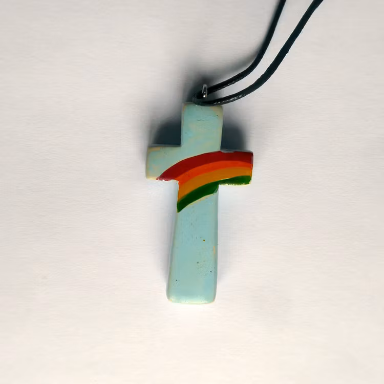 Halssmycke Kors i täljsten med påmålad regnbåge som hängsmycke. Med kraftigt bemullssmöre, längden kan varieras.Fair Trade från Kenya.