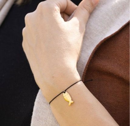 Armband 'Faith' med fisk (ichtys) som smycke, gulddouble 24 karat. Fairmined i Colombia. Fair Trade. Bild med armband runt handleden.