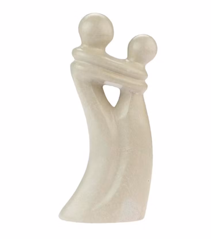 Skulptur Sammanflätade föreställer två människor som står tätt intill varandra och omfamnar varandra. Naturtäljsten från Kenya, för Fair Trade.