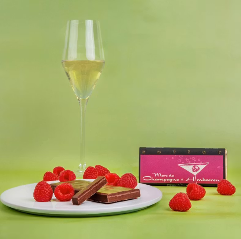 Zotter Champagne Hallon, utsökt chokladpralin.Stämmningsfull bild med Zotter pralin, levande ljus och hallon.