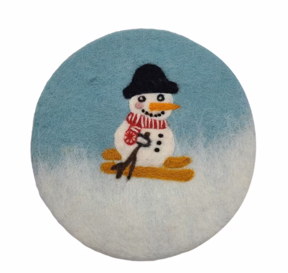 Underlägg i vit och blå, Glad snögubbe med hatt och sjal på skidor. Runt, tovat.