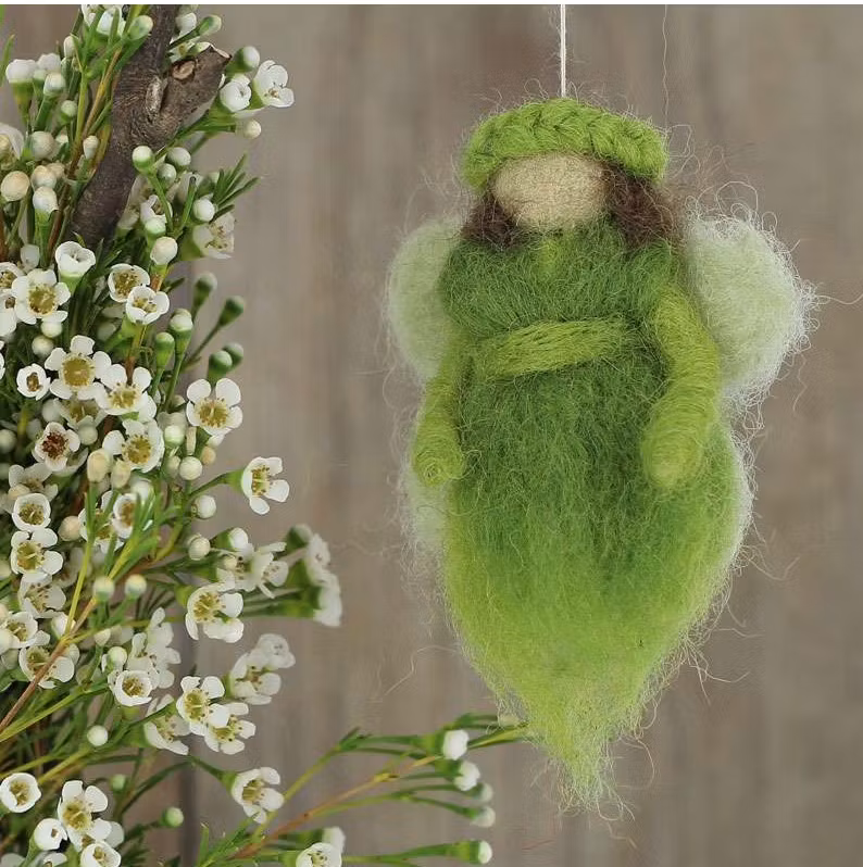 liten glad och god fe eller ängel eller kanske älva eller skyddsängel i grön färg. Bild med deko.