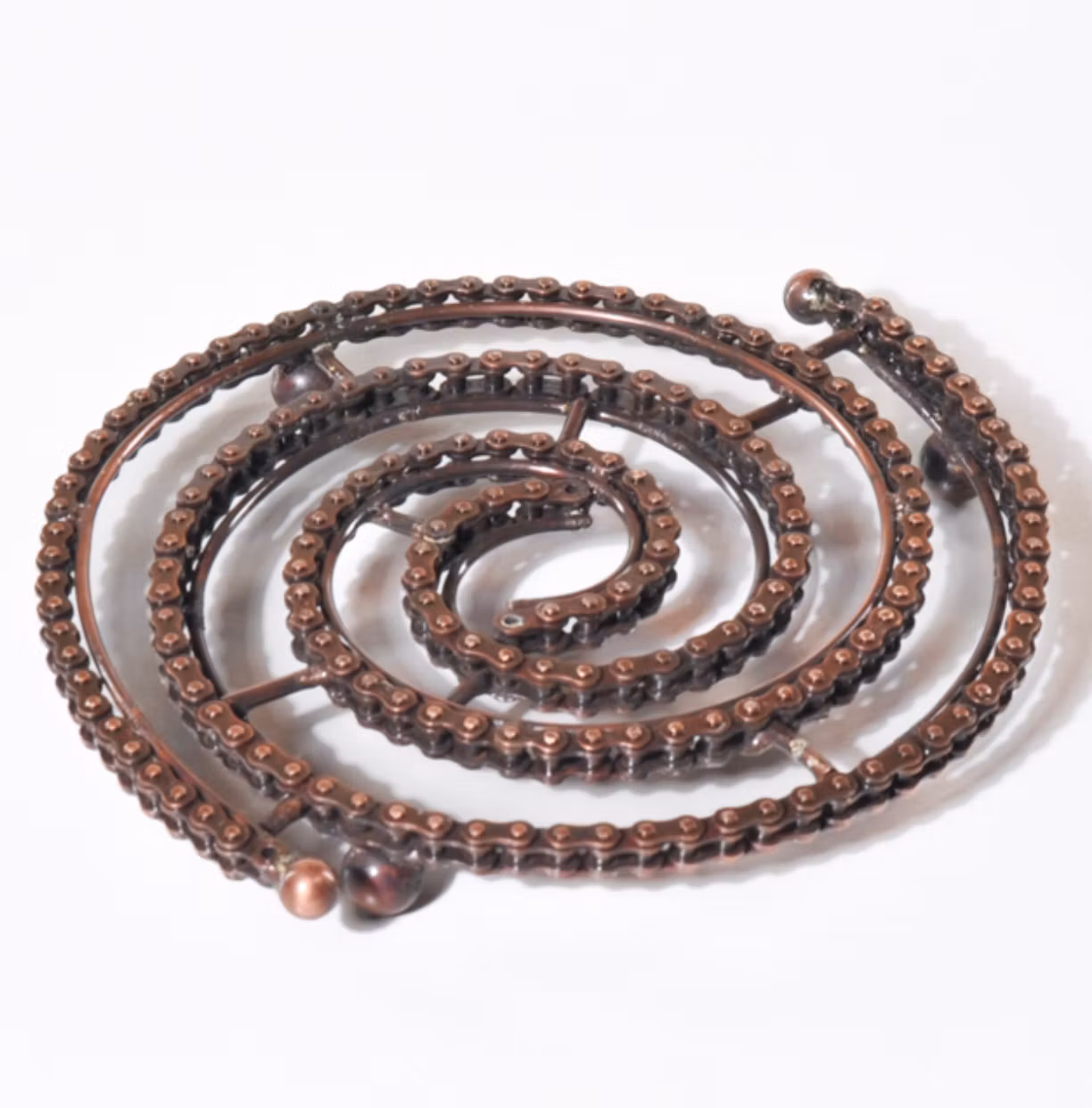 Grytunderlägg Cykelkedja, kopparglänsande, upcycling. med små svarta gummiben. Fair Trade.