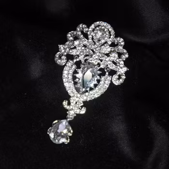 Brosch, silverfärgad metall med strass. Art 33.