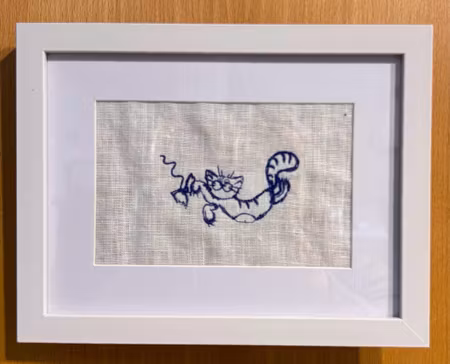 Broderad tavla med en katt som leker