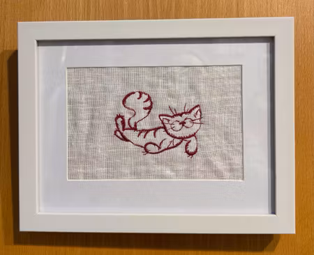 Broderad tavla med söt katt som ligger ner.