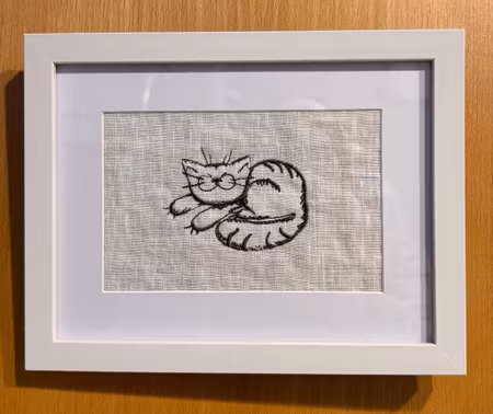 Broderad tavla med en gullig katt som sover