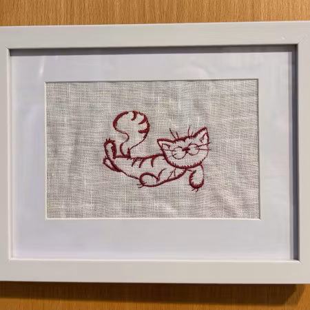 Broderad tavla med söt katt som ligger ner. Välj färg på brodyren