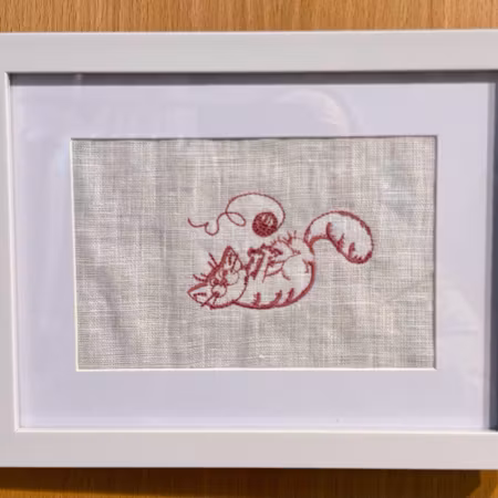 Broderad tavla med söt katt som leker med garnnystan