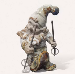 Keramik tomte som skidar och har metall stavar