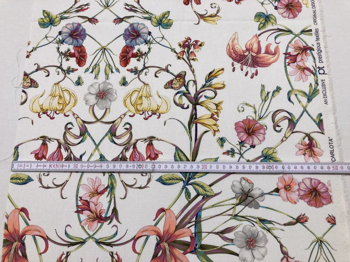 Närbild av Carlotta stuvbit med tumstock som visar den 50 cm breda tygbiten och blommönstrets detaljer.