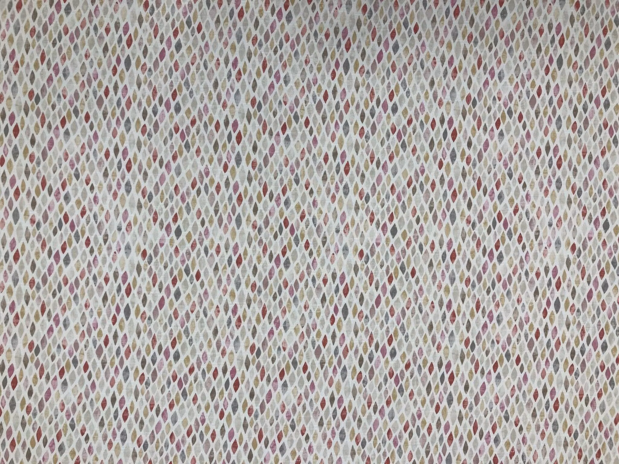 Mosaik grafiskt småmönstrad metervara med små romber i rosa, vinrött, gult, beige, brunt och naturvitt.