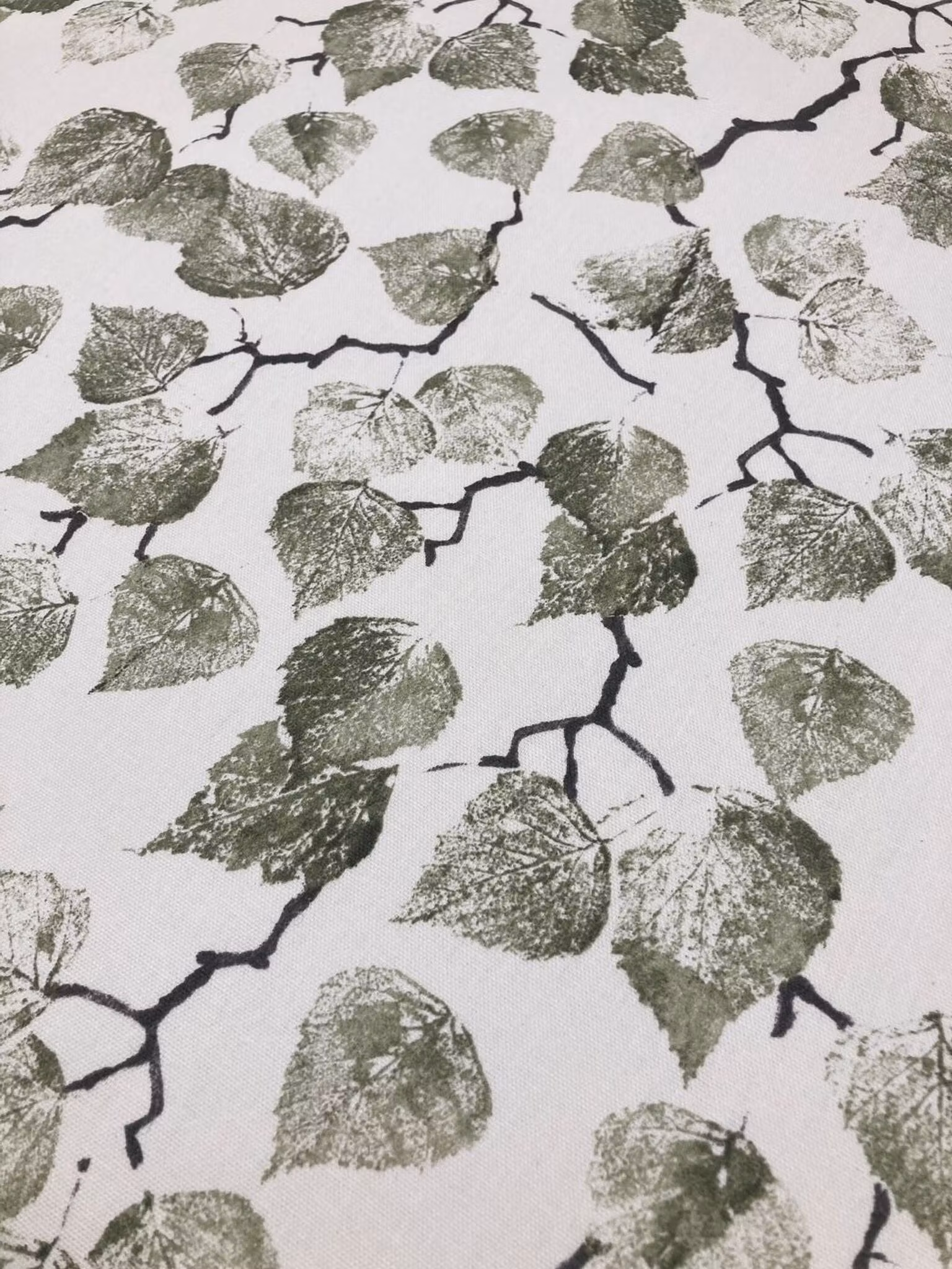 Närbild av Björklöv tyg med botaniskt bladmönster i gröna toner