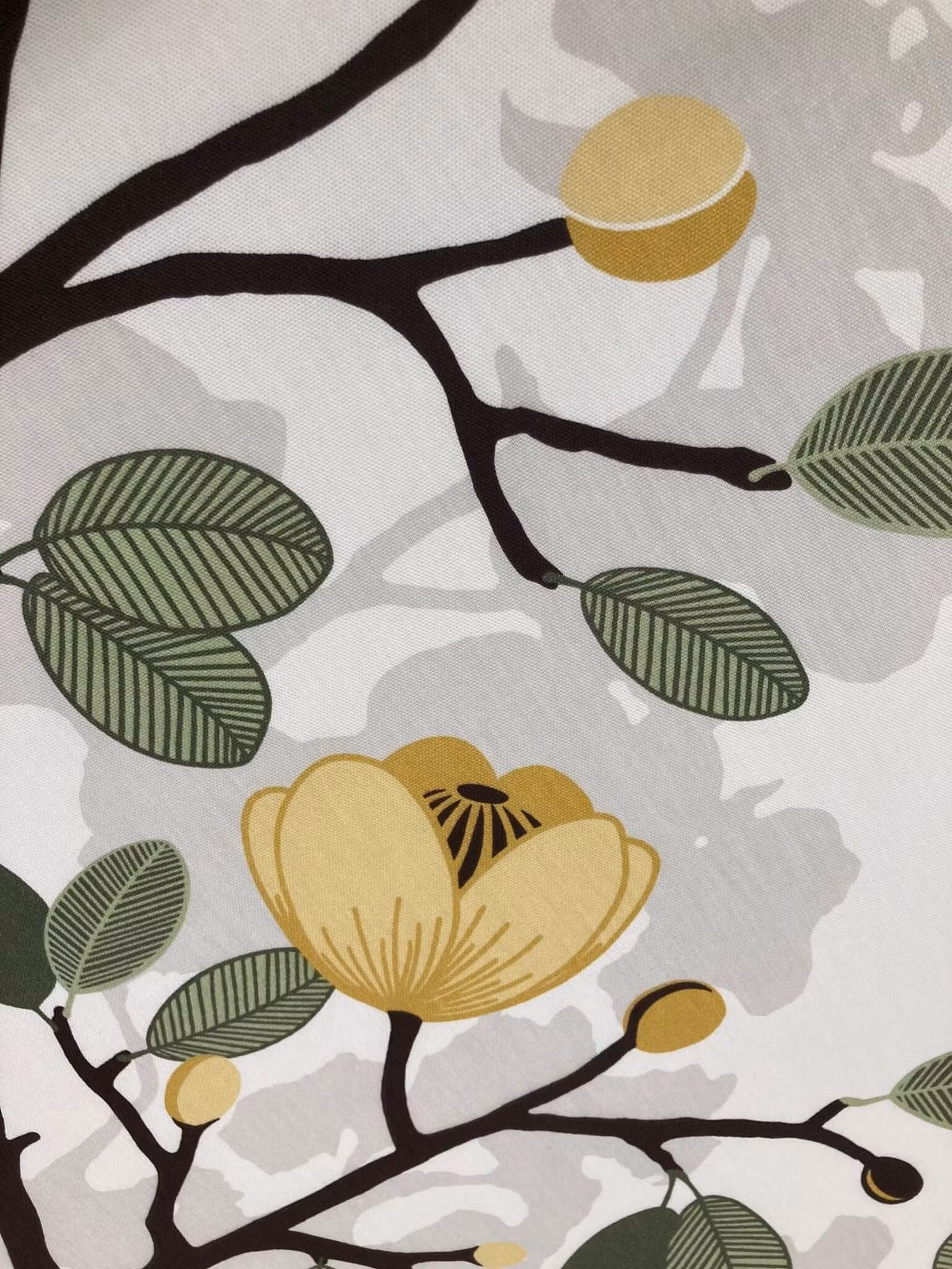 Närbild av Ofelia inredningstyg med gula blommor, gröna blad och dekorativa grenar