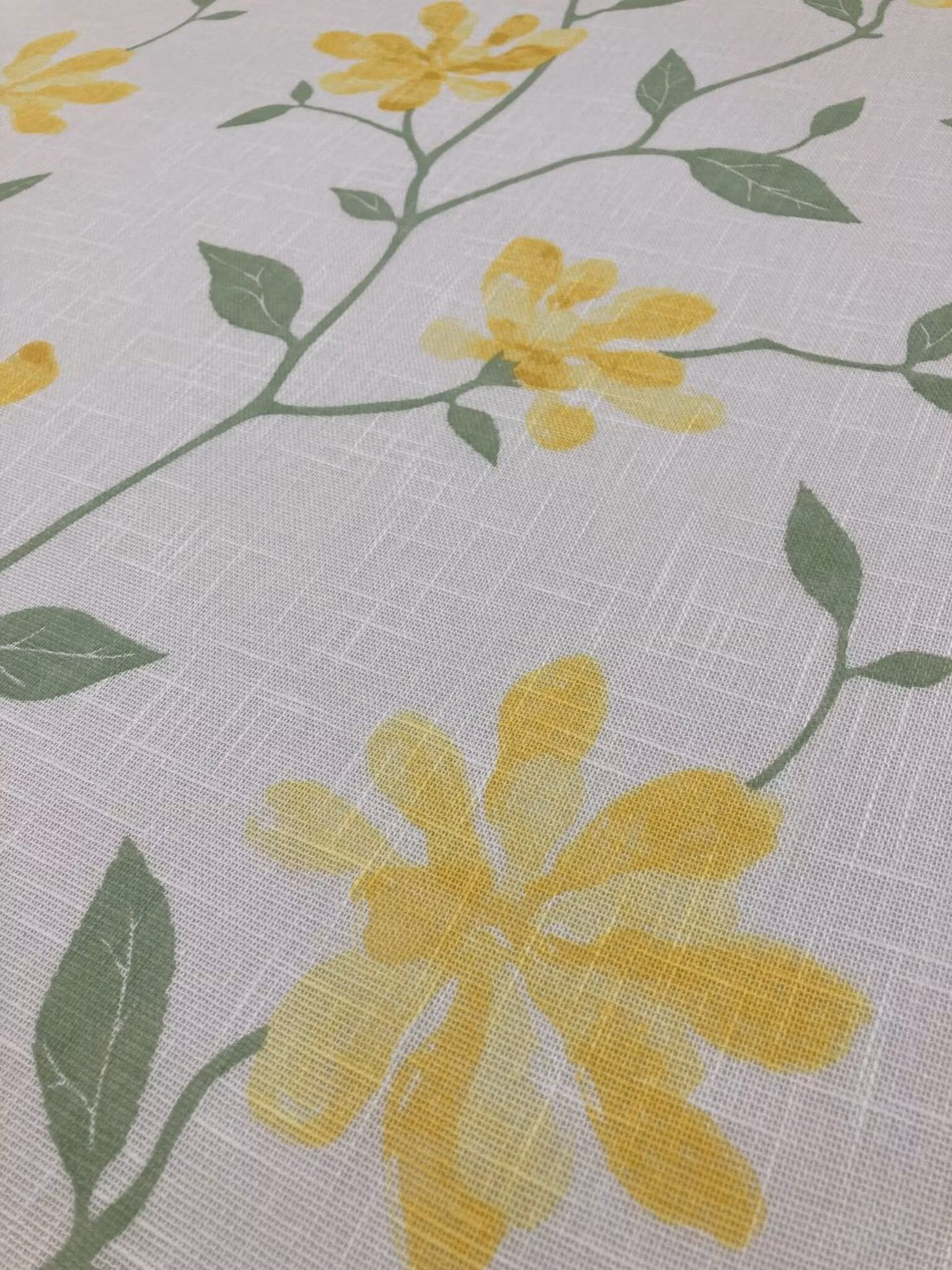 Närbild av Louise gul gardintyg med blommönster och luftig vävd struktur