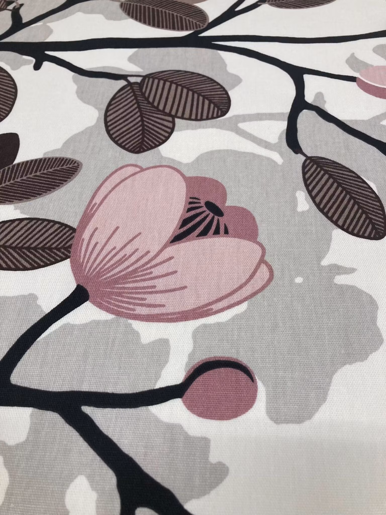 Närbild av Ofelia inredningstyg med rosa blommor, bruna blad och dekorativa grenar