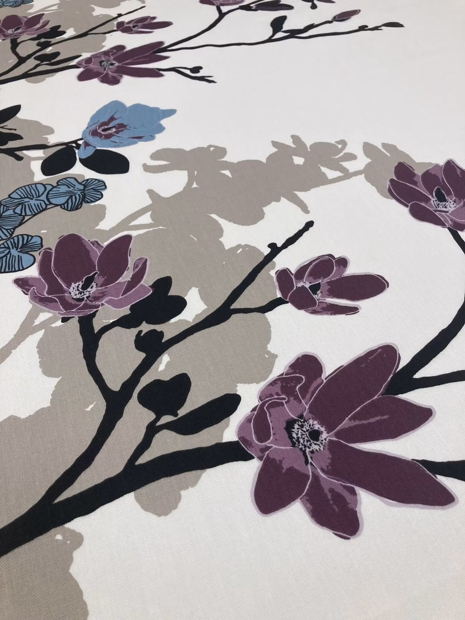 Närbild av Grandiflora multi som visar magnoliakvistar med plommonlila blommor och detaljrik bomullsstruktur.